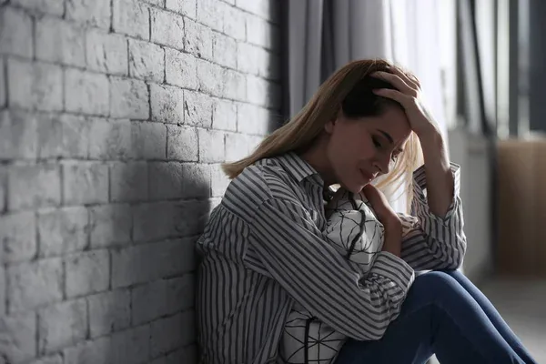 Junge Frau sitzt erschöpft an einer Wand – nicht jede Lebenskrise löst sich von allein